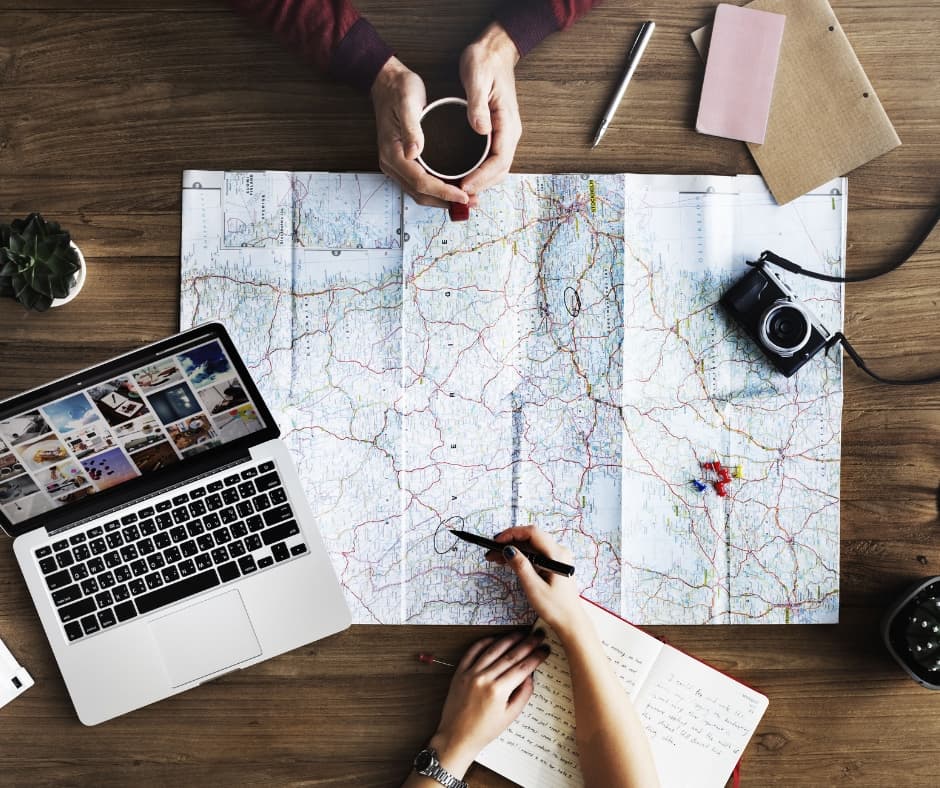 Travellers comparing a map with a laptop while planning a route